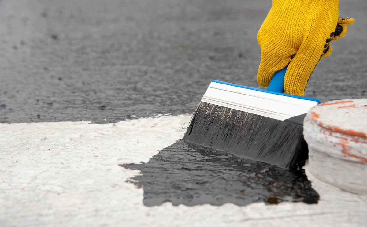 Aplicação de impermeabilizante com trincha sobre superfície de concreto