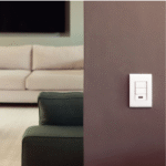 Interruptor em parede com sofá ao fundo.